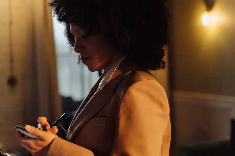 Woman writing her service options and business goals in a notepad, planning her virtual assistant business