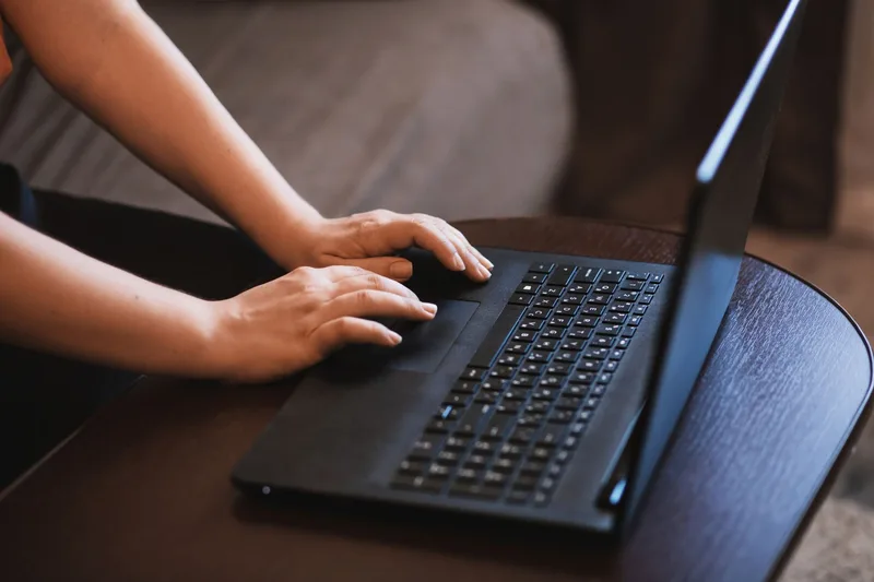 Close-up of hands typing on a laptop keyboard while screening job candidates online