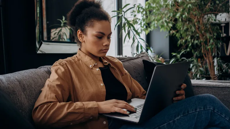 Woman at a clean desk typing on her laptop in a bright home office