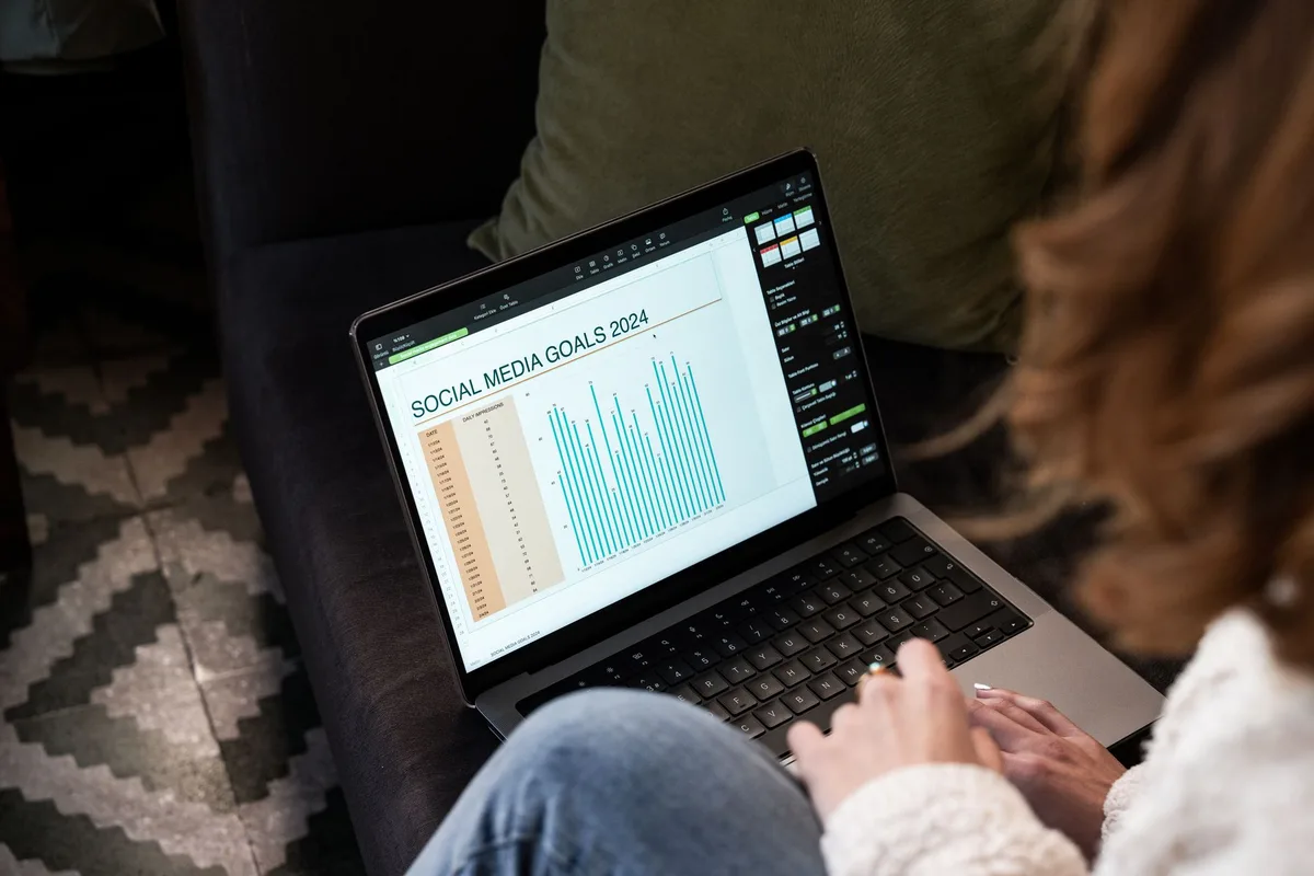 A woman reviewing Pinterest content goals and analytics on a laptop at home