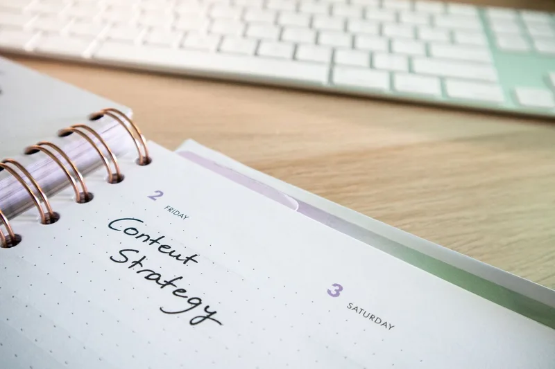 A Pinterest content calendar planned out in a notebook next to a laptop keyboard