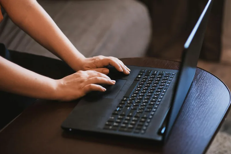 Professional browsing remote job listings across multiple platforms on a laptop at a home desk