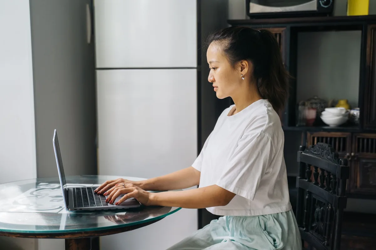 Young woman working on a laptop at a table in a home office