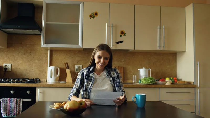 Woman smiling while reading feedback at a kitchen table