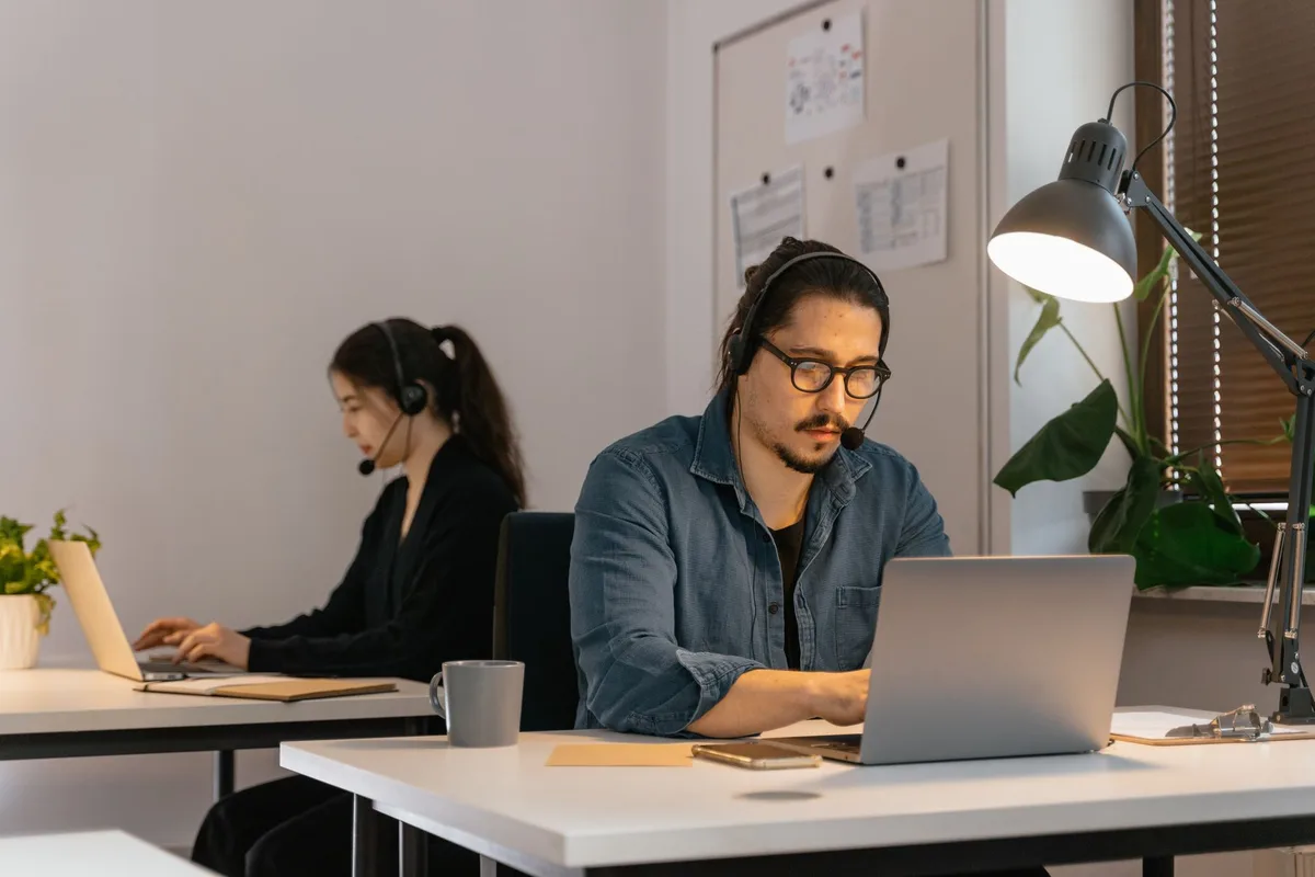 Two virtual assistants working with headsets and laptops — the team model that powers a VA agency