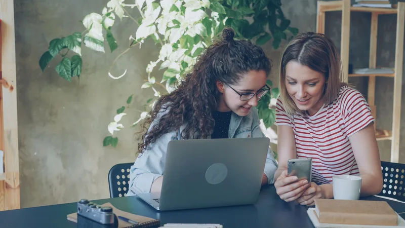 Two professionals collaborating on digital work from a shared workspace