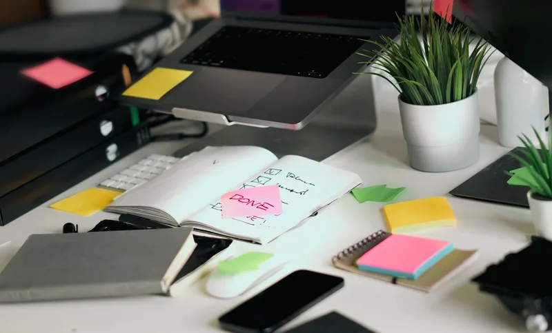 Desk with an open notebook checklist, sticky notes, and a laptop, representing a decision checklist before paying for a course