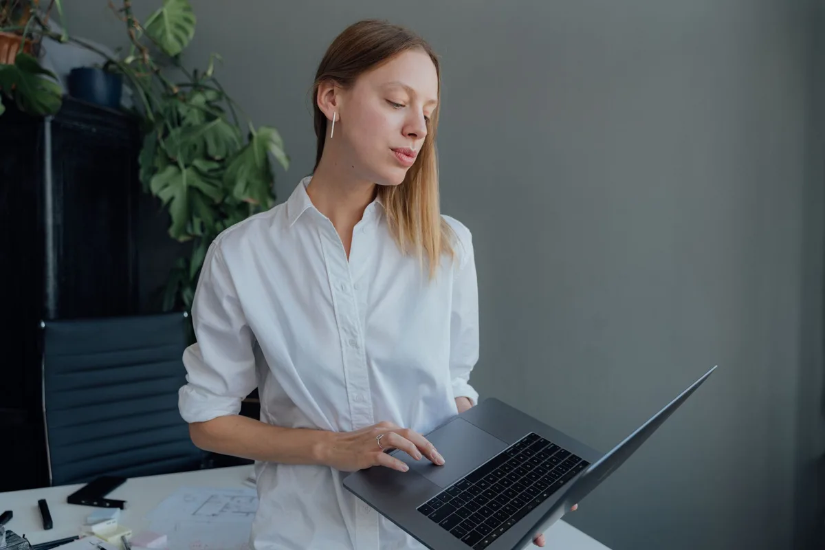 A woman working as a virtual assistant at a laptop in a bright home office