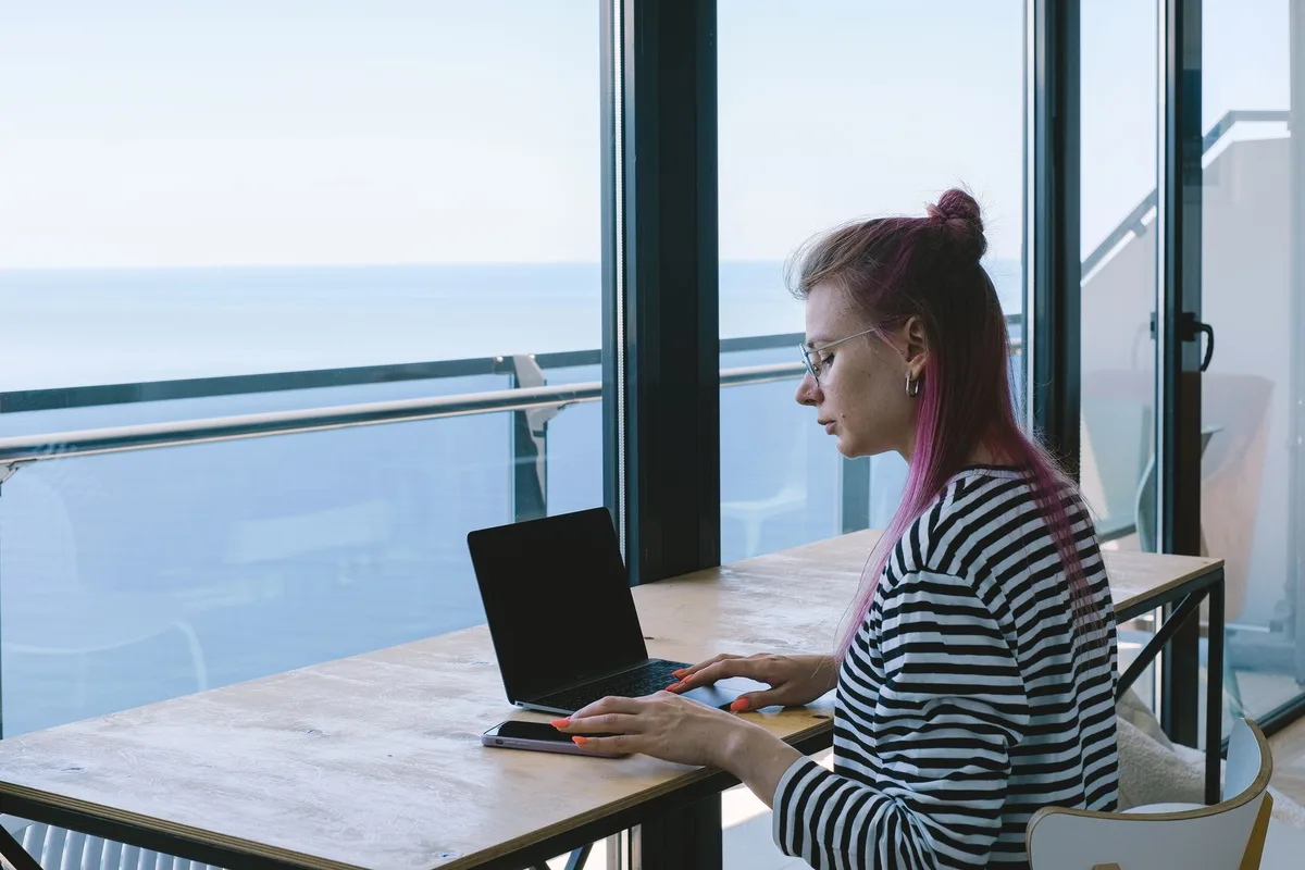 A professional woman working on a laptop from a bright home setting