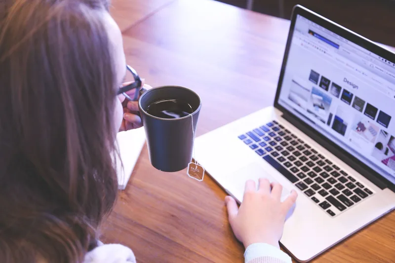 A woman working at a home office desk with a laptop and a cup of coffee