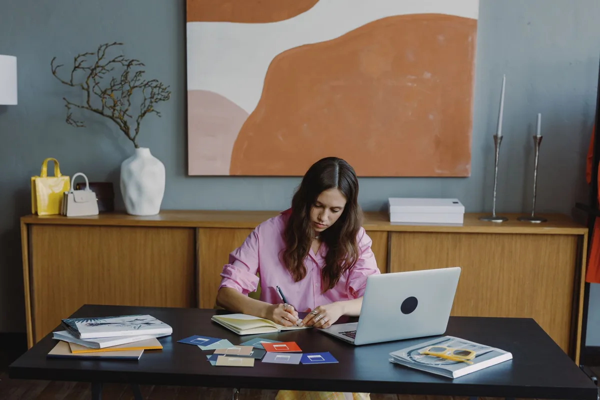 Woman working remotely at a laptop in a bright home office, building her virtual assistant resume