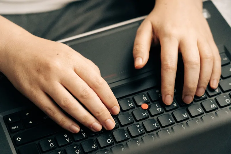 Close-up of hands typing on a laptop keyboard